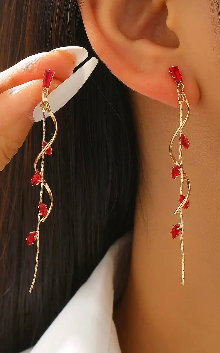 Earrings with red stones being worn and held up to the ear.