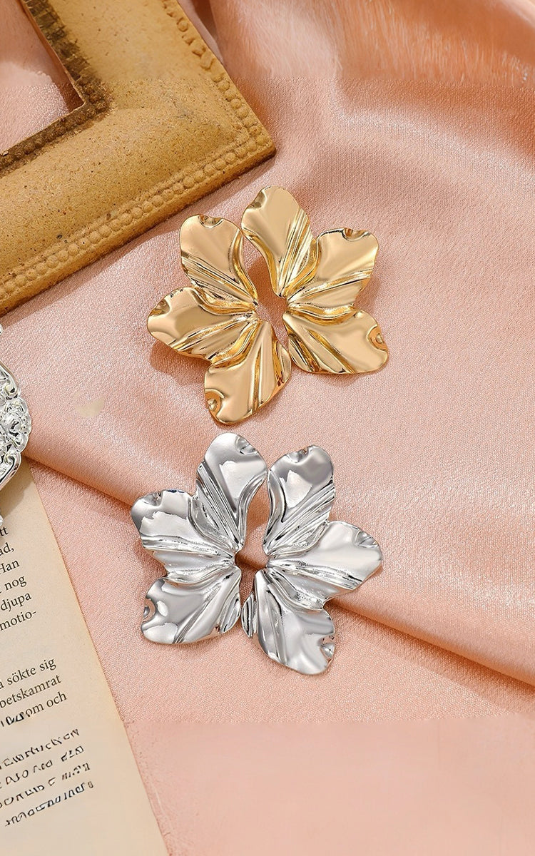 Gold and silver floral brooches on a pink fabric background