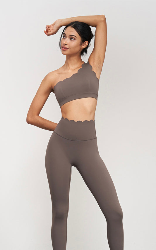 Woman wearing a brown sports bra and leggings on a white background