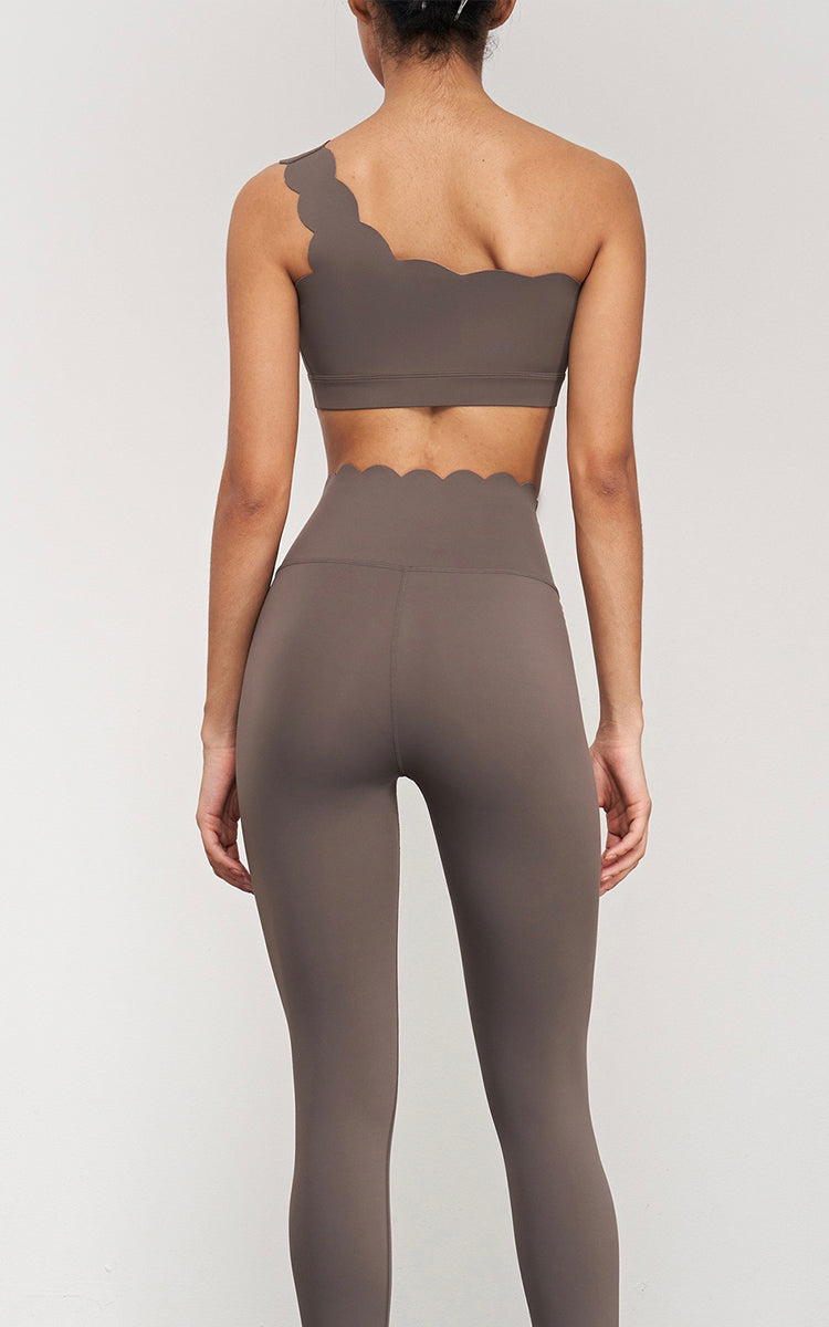 Model wearing a brown sports bra and leggings set on a light gray background