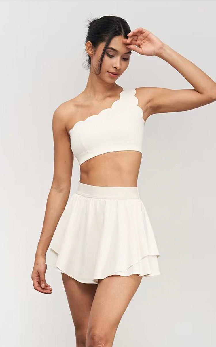Model wearing a white one-shoulder top and skirt set on a plain background