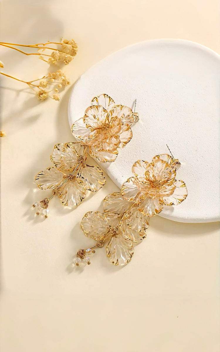 Yellow floral earrings on a white plate with a beige background