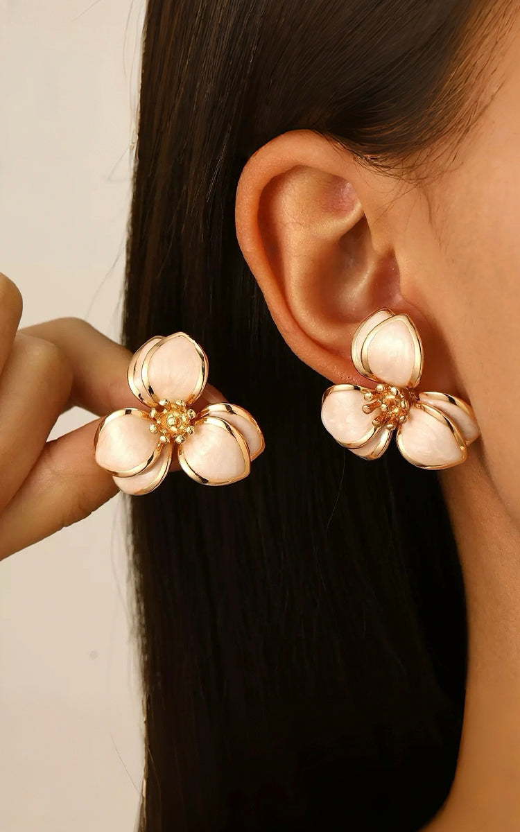 Close-up of a person wearing floral earrings with a neutral background